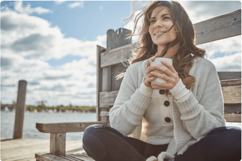 Woman sitting calmly outdoors representing emotional steadiness, recovery, and nervous system regulation